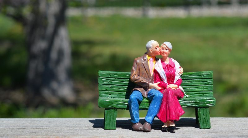 Älteres sich küssendes Liebespaar auf einer Bank