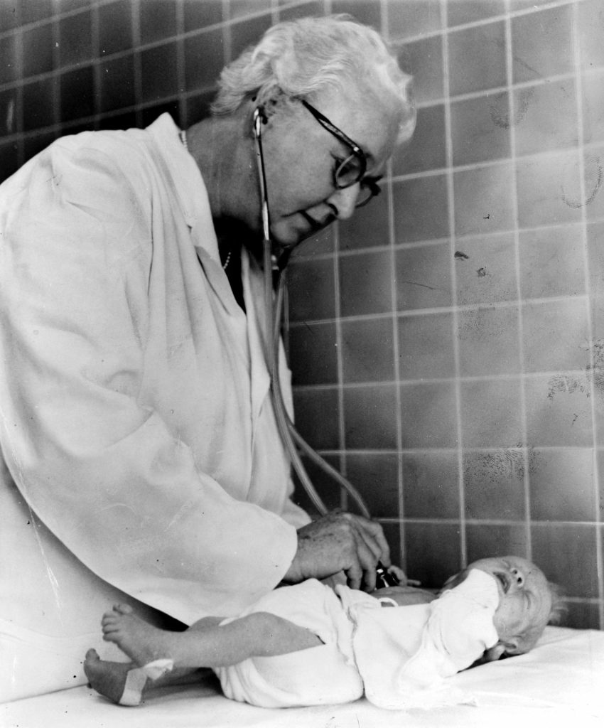Virginia Apgar untersucht ein Neugeborenes.